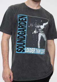 Black cotton t-shirt featuring a graphic print of a musician with the text "SOUNDGARDEN LOUDER THAN LOVE" in blue and white accents.