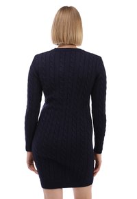 Abito lavorato a maglia blu navy con motivo a trecce, maniche lunghe e silhouette aderente, che si ferma sopra il ginocchio.