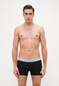 Fekete boxer nadrág világoskék elasztikus derékkal, amelyen a "TOMMY HILFIGER" felirat található. Simára kezelhető anyag és szoros fazon.