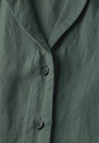 Camicia verde con colletto, in tessuto testurizzato, dotata di un bottone nero con il testo "CECIL", dettaglio di cuciture e vestibilità rilassata.