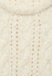 Pull en laine couleur crème avec motifs torsadés et ajourés, doté d'un col rond côtelé.