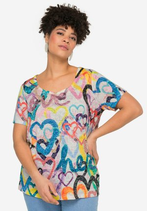 T-shirt à manches courtes et encolure dégagée en tissu léger présentant un motif de cœurs multicolores avec des teintes de rose, bleu, jaune et noir.