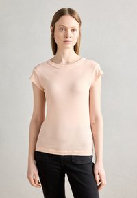 Vaaleanpunainen puuvillainen slim fit -t-paita, jossa on lyhyet hihat ja pyöreä kaula-aukko. Paita on sileätekoinen ja siinä on minimaalinen sauman yksityiskohtia.