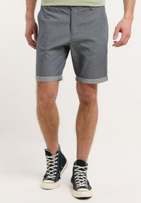 Pantaloni corti grigi a righe con risvolti, tasche laterali e una design frontale piatto, abbinati a sneaker alte blu navale.