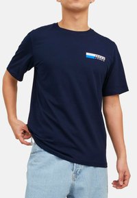 Navyblaues Baumwoll-T-Shirt mit Rundhalsausschnitt, kurzen Ärmeln und einem Logoschriftzug mit blauen und weißen Akzenten auf der Brust.