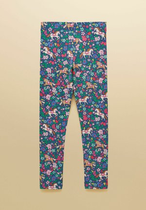 Modré legíny s barevným květinovým vzorem a bílými kolotočovými koníky s růžovými sedly rozmístěnými po látce.