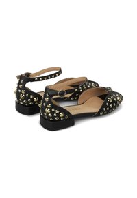 Bailarinas negras con un diseño abierto, adornadas con tachuelas metálicas. Presentan una correa con hebilla y un tacón bajo tipo bloque para mayor soporte.