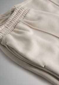 Beežid puuvillased püksid tekstuurse kangaga, millel on elastne vöökoht, küljetaskud ning mugav lõige.