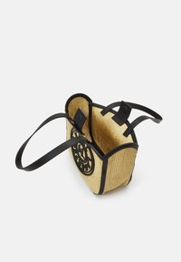 Petit sac à main en paille tissée avec garniture en cuir noir, double bandoulière et logo circulaire noir sur le côté, présenté ouvert avec fermeture magnétique.