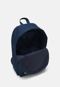 Zaino blu navy con parte superiore arrotondata, scomparto principale con zip e tasca frontale con pattina. Realizzato in tessuto resistente con una texture liscia.
