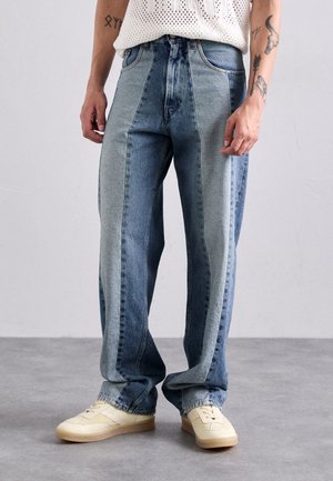 Light denim jeans featuring an uneven color panel design with a mix of dark and light shades, wide legs, and a standard waistband.