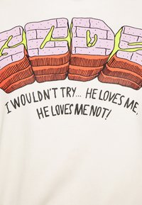 Weißes Baumwoll-T-Shirt mit einem bunten Grafikdesign von Bonbonblöcken in Pink und Orange, ergänzt durch grüne Akzente und fett gedruckten schwarzen Text darunter.