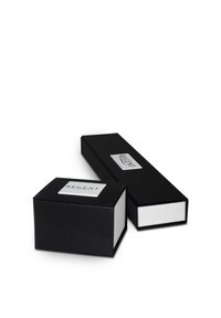 Des boîtes cadeaux rectangulaires noires avec des intérieurs blancs, l'une plus grande et allongée, arborant une étiquette en relief argentée avec "REGENT" sur le dessus.