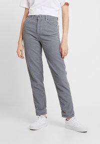 Grå kordflamsbyxor med rak bendesign, knäppning och dragkedja, samt hög midja. Matchas med vita sneakers.