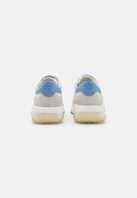 Grå semsket og hvit mesh sneakers har en lys blå hælaccent og en teksturert såle. Bakvisningen viser en logo på hæltabben.