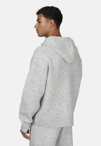 Jasnoszara bluza z kapturem z prążkowanymi mankietami i dołem, wykonana z miękkiego materiału. Posiada luźny krój i duży kaptur.