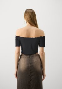 MustMust musta varrukatega must ribatud top, mis on kantud kõrge talje pruunist denimseelikust, millel on lukk taga.