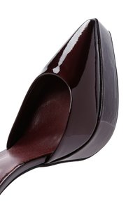 Burgundy patent leather high heel with a pointed toe and curved cutout design. Smooth texture and glossy finish with a visible platform.