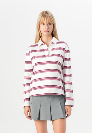 Long-sleeve white polo with maroon horizontal stripes, featuring a pointed collar and a relaxed fit, paired with a gray pleated skirt.