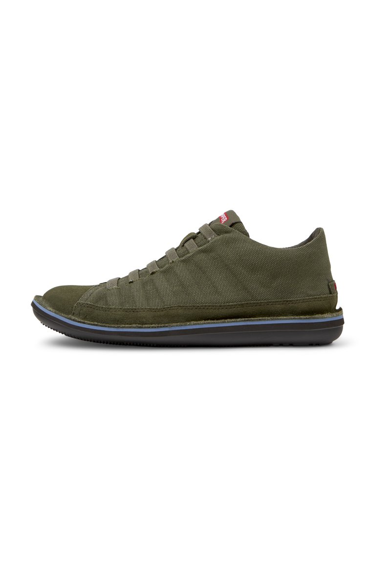 Olive green sneakers made of textured fabric with a suede toe cap. Features a lace-up design, black rubber sole, and small red logo accent.