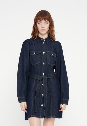 Robe en denim à manches longues, col et devant boutonné. Dotée de deux poches poitrine, d'une taille ceinturée et d'une couleur bleu foncé avec des coutures discrètes.
