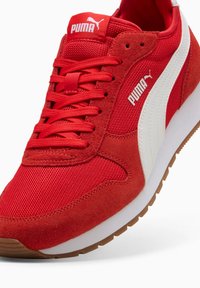 Crvene atletske tenisice s mrežastim gornjim dijelom i zamščenim detaljima. Imaju bijeli logo, ravne vezice i gumeni potplat.