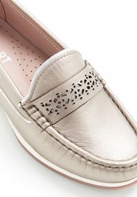Mocassino slip-on in oro metallico con dettagli perforati sulla tomaia, bordi cuciti e soletta imbottita. Finitura liscia con punta arrotondata.