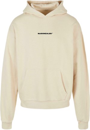 Hettegenser i lys beige med frontlomme. Har svart tekst "MJGONZALES™" på brystet. Myk stoffkvalitet med ribbestrikkede ermer.