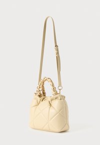 Τσάντα χειρός σε κρεμ χρώμα με καπιτονέ σχέδιο, που διαθέτει πλεχτό χερούλι στην κορυφή και ρυθμιζόμενο λουράκι. Ομαλή υφή με διακοσμητικά στοιχεία σε χρυσό τόνο.