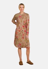 Beige tuniekjurk met floral borduurwerk, lange mouwen, knoopsluiting aan de voorkant en een golvende zoom. Voorzien van levendige, multikleurige bloemen en bladeren.