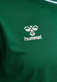Grön sporttröja i mjuk kvalitet, med en vit logotyp av en bi och namnet "hummel" under.