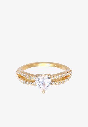 Gouden ring met een hartvormige, transparante steen in het midden, geflankeerd door twee rijen kleine heldere stenen langs de band.