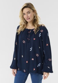 Blouse marine à manches longues, ornée de motifs brod�és colorés incluant des cœurs et des oiseaux, avec un col à cordon.