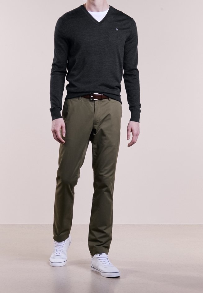 Dunkelgrauer V-Ausschnitt-Pullover, olivgrüne Hose, weiße Sneaker. Besitzt ein kleines Logo auf der Brust, was ein lässiges Outfit schafft.