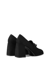Scarpe nere in suede con tacco alto e squadrato. Presentano una punta rotonda e un accento decorativo in metallo sulla tomaia.