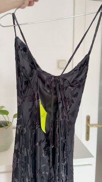 Juoda su gėlėmis motyvuota suknelė su plonomis petnešėlėmis, turinti minkštą tekstūrą ir surištą nugaros detalę. Į komplektą įeina pakabintas kainų etiketė.