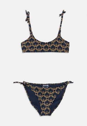 Temno moder bikini komplet z vzorcem zlatih verižnih členov. Zgornji del ima nastavljive naramnice; spodnji del je opremljen z bočnimi vezalkami za boljše prileganje. Gladek tekstura.
