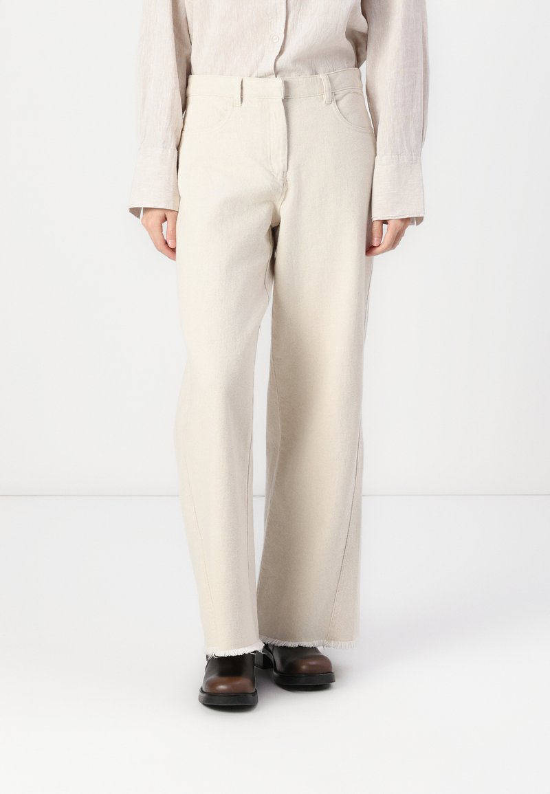 Light beige wide-leg trousers made of soft fabric with a raw hem and belt loops, featuring standard pockets and a relaxed fit.