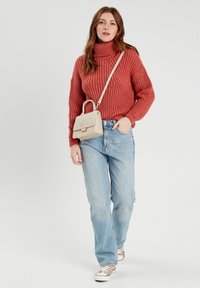 Pull col roulé en terracotta tricoté, coupe décontractée, associé à un jean droit taille haute bleu clair et un sac à épaule beige.