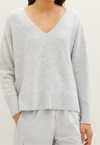 Pull gris clair à col en V en tissu doux, doté d'un ourlet et de poignets côtelés. Coupe décontractée avec épaules tombantes et texture confortable.