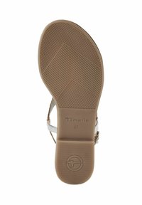 Sandal sål med en slät, tan gummiyta som har horisontella och diagonala spår. Varumärket "Tamaris" tryckt i en subtil design.