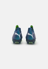 Scarpe da calcio Puma con un design blu scuro e teal, caratterizzate da una tomaia testurizzata, dettagli verdi e un logo bianco sul tallone.