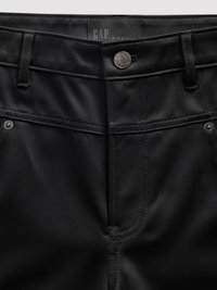Pantalon en tissu noir à texture lisse, doté d'une fermeture à bouton, de passants pour ceinture et de détails de couture subtils. L'étiquette indique "GAP Studio".