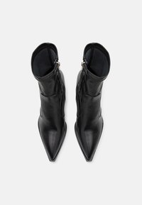 Sorte læder ankelstøvler med spids tå, lynlås i siden og struktureret indvendig foring. Glat finish med minimale detaljer.