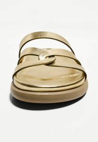 Gold metallic sandals with multiple thin straps and a rounded toe design, featuring a smooth texture and flat, beige sole.