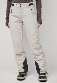 Beige skibroek met donkerblauwe accenten, waterdicht materiaal, zakken met rits aan de zijkant, verstelbare taille en een ontspannen pasvorm voor comfort.