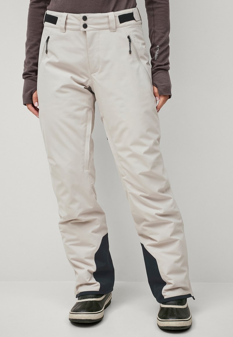 Beige skibroek met donkerblauwe accenten, waterdicht materiaal, zakken met rits aan de zijkant, verstelbare taille en een ontspannen pasvorm voor comfort.