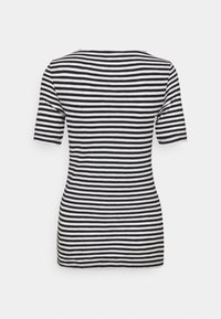 Camiseta de rayas blanco y negro con mangas cortas, escote redondo y tejido suave. La vista trasera muestra rayas horizontales uniformemente espaciadas.
