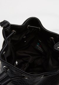 Czarna torba typu bucket z teksturowaną powierzchnią, materiałową wyściółką, srebrnymi elementami metalowymi, zapięciem na troczek i wewnętrzną kieszenią.