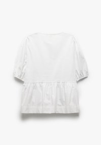 Blouse blanche avec des manches bouffantes et un ourlet à volants. Tissu en coton lisse, col rond et détails de couture subtils. Design simple.